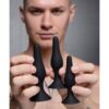 A male model holding three black silicone plugs