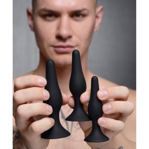 A male model holding three black silicone plugs