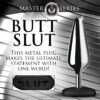 A metal butt plug labeled 'BUTT SLUT', with a close-up of the word on a black base