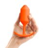 A hand holds a vibrant orange silicone toy