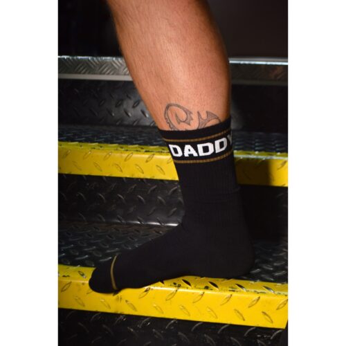 A leg with a tattoo wearing a sock that says 'DADDY'