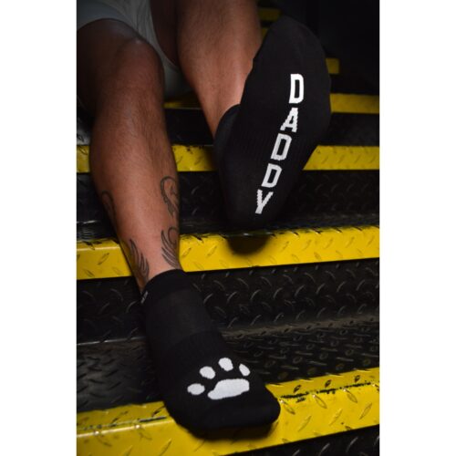 Feet in black socks with 'DADDY' print and paw print