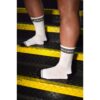 A person's legs in white socks with 'DISCREET' branding, on yellow-striped stairs