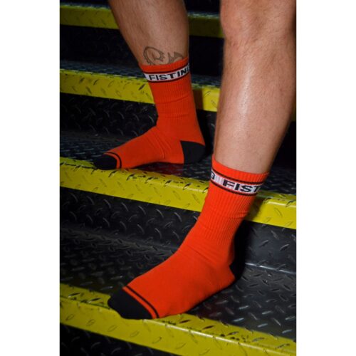 Person's legs in orange FISTING socks, standing on yellow metal steps