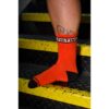 Orange socks with 'FISTING' band, worn on a foot on yellow steps