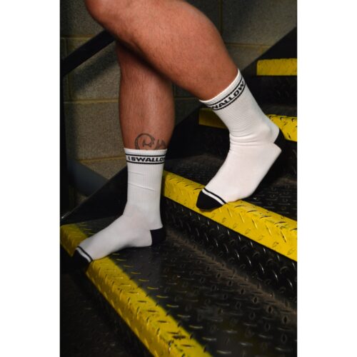 White socks with black trim on a person's legs, on a staircase with yellow markings