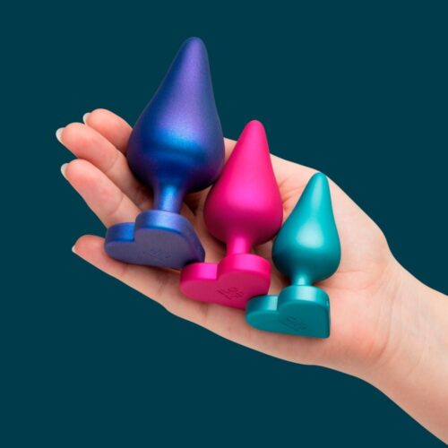 Three colorful anal plugs in a hand