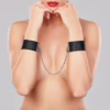 Black wrist cuffs with connector chain, worn by a model with red lips