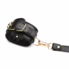 Black leather bondage harness with gold hardware and bows