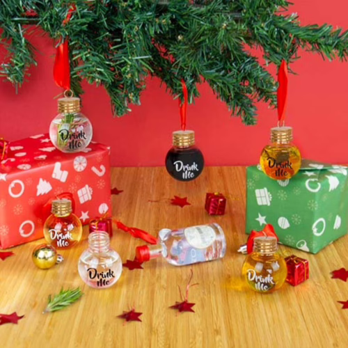 Miniature bottles labeled 'Drink Me' hanging from a tree, with festive gifts below