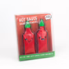 Stay warm with these fun hot sauce hand warmers, available at The Loving Company. Two hot sauce-shaped hand warmers with smiling faces in a clear package