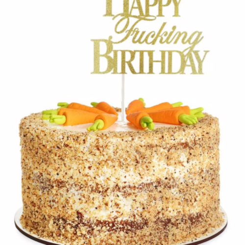 A birthday cake with a gold 'Happy Fucking Birthday' topper, topped with carrot decorations