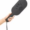 A hand holding a black paddle with a paw print cutout