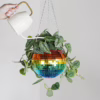 Add a splash of color to your home with this whimsical disco ball hanging planter! Rainbow disco ball hanging planter with green leaves;