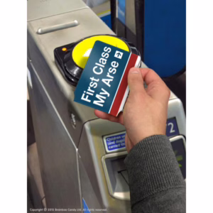This cheeky ticket brings a smile to your commute with its playful message. Hand holding a 'First Class My Arse' ticket above a fare gate, available at The Loving Company.